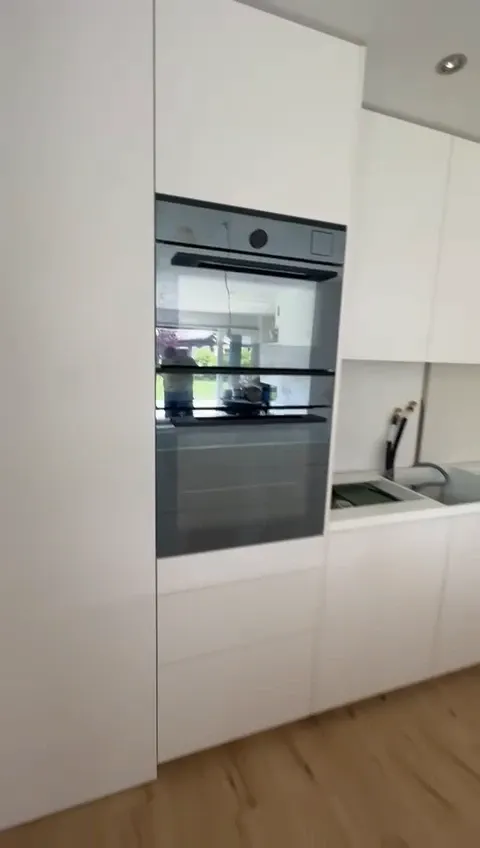 Weisse Küche mit Backofen im Hochschrank, Unterschränken und Spüle auf Eichenparkett