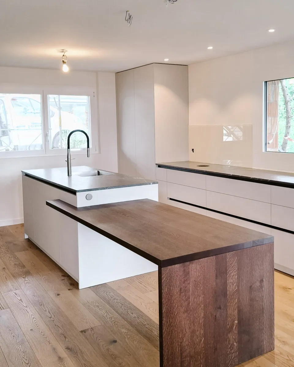 Küche mit weisser Kochinsel und angesetztem Esstisch aus dunklem Holz